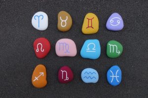 Die zwölf Tierkreiszeichen abgebildet auf bunten Steinen.