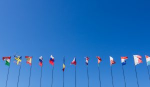 Die interkulturelle Kommunikation, dargestellt durch verschiedene Länderflaggen vor einem blauen Himmel.