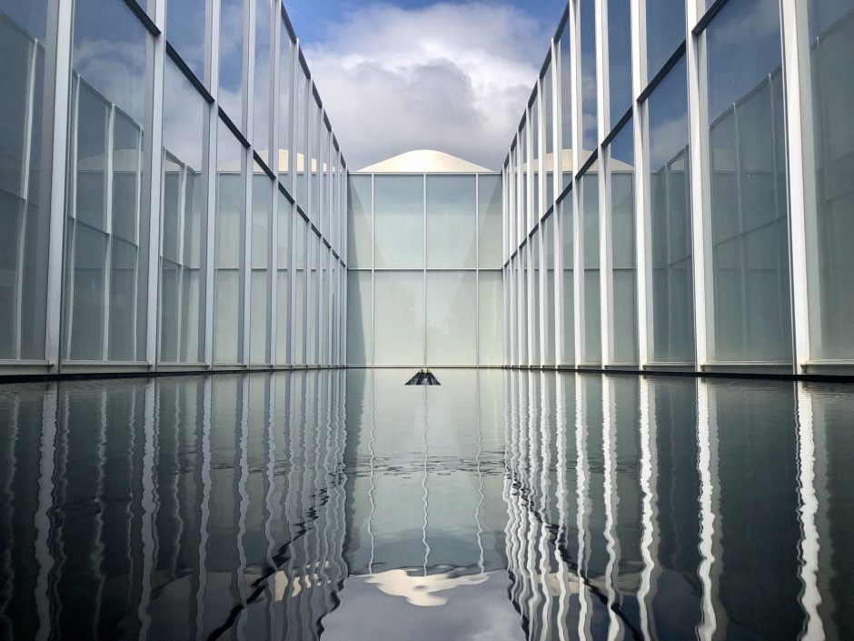 Ein Gewässer, das wie der Human Design Typ Reflektor seine Umgebung widerspiegelt, in diesem Fall ist es ein hohes Gebäude mit Glasfassaden.